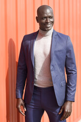 Portrait of smiling businessman wearing blue suit and grey turtleneck pullover - JSMF00895