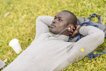 Businessman listening music with earphones and smartphone - JSMF00911
