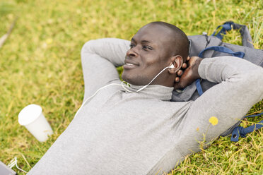 Smiling businessman listening music with earphones - JSMF00912