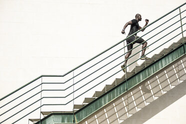 Mann in schwarzer Sportkleidung läuft eine Treppe hinauf - JSMF00938