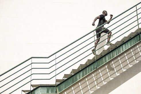 Mann in schwarzer Sportkleidung läuft eine Treppe hinauf - JSMF00938