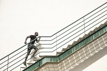 Mann in schwarzer Sportkleidung läuft eine Treppe hinauf - JSMF00939