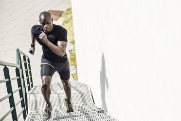 Mann in schwarzer Sportkleidung läuft eine Treppe hinauf - JSMF00940