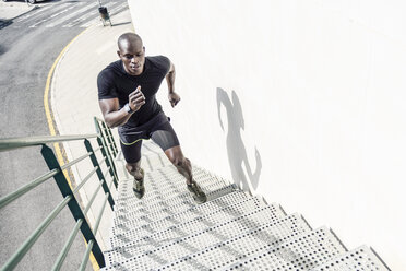 Mann in schwarzer Sportkleidung läuft eine Treppe hinauf - JSMF00941