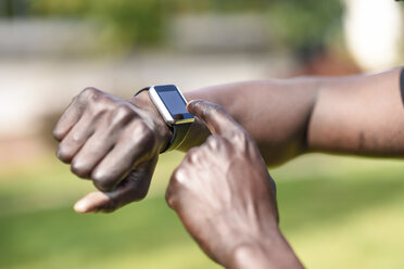 Runner checking smart watch fitness tracker, close-up - JSMF00945
