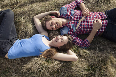 Glückliches junges Paar auf einer Wiese liegend - PNEF01316