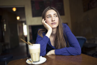 Young woman sitting at table in a cafe looking sideways - PNEF01317