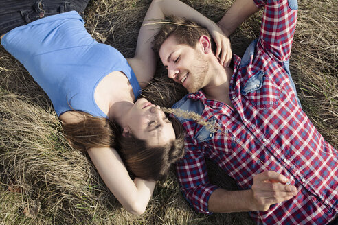 Glückliches junges Paar auf einer Wiese liegend - PNEF01318