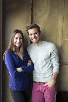 Porträt eines glücklichen jungen Paares, das an einer Mauer steht - PNEF01325