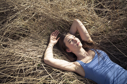 Entspannte junge Frau auf der Wiese liegend - PNEF01329