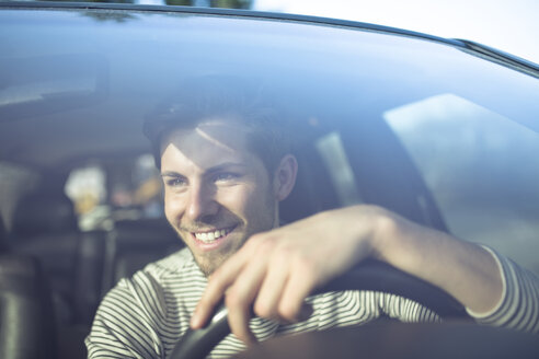 Lächelnder junger Mann am Steuer eines Autos - PNEF01341