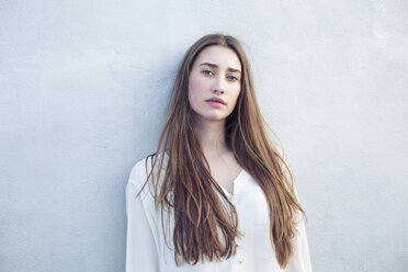 Portrait of serious young woman at a wall - PNEF01350