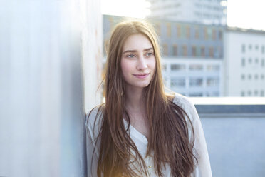 Portrait of smiling young woman leaning against a wall - PNEF01351