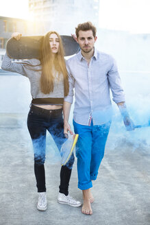 Porträt eines jungen Paares mit Rauchfackel und Skateboard - PNEF01355