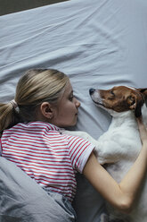 Blondes Mädchen liegt auf dem Bett und kuschelt mit ihrem Hund - JPF00377