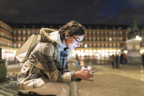 Spanien, Madrid, Plaza Mayor, junge Frau benutzt ihr Smartphone - WPEF01384