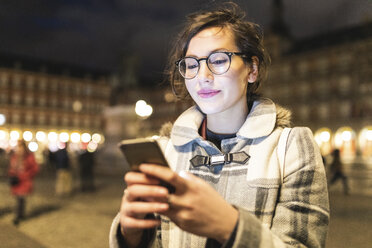 Spanien, Madrid, Plaza Mayor, junge Frau benutzt ihr Smartphone - WPEF01387