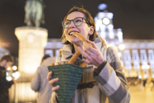 Spanien, Madrid, junge Frau in der Stadt bei Nacht, die typische Churros mit Schokolade isst - WPEF01406