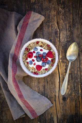 Schüssel Müsli mit griechischem Joghurt, gepopptem Quinoa, Himbeeren, Heidelbeeren und Granatapfelkernen, von oben, lizenzfreies Stockfoto