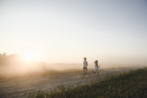 Girl and boy running on a rural dirt track - EYAF00055