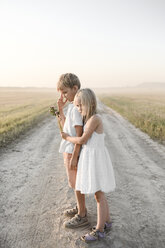 Girl hugging boy on a rural dirt track - EYAF00058