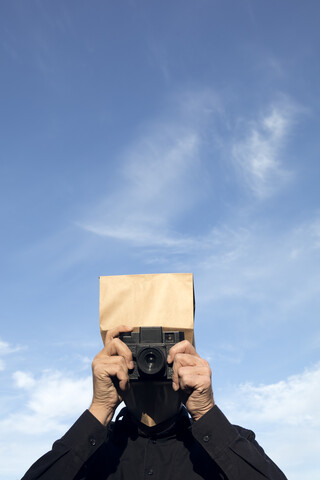 Mann mit Papiertüte über dem Kopf beim Fotografieren, lizenzfreies Stockfoto