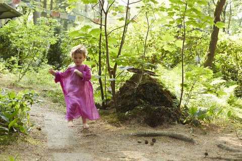 Kleines Mädchen in rosa Tunika läuft in der Natur, lizenzfreies Stockfoto