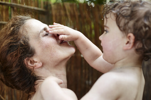 Mutter und kleine Tochter nehmen eine Dusche im Freien und haben Spaß, lizenzfreies Stockfoto