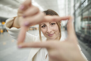 Porträt einer lächelnden jungen Geschäftsfrau, die auf dem Flughafen einen Fingerabdruck macht - PNEF01371