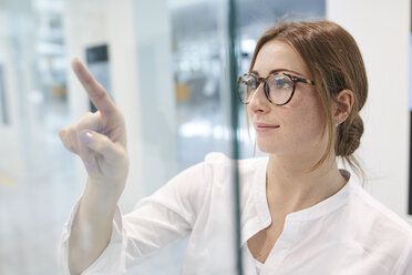 Junge Geschäftsfrau berührt virtuellen Touchscreen - PNEF01374