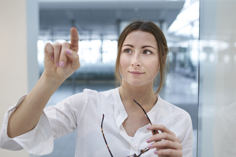 Junge Geschäftsfrau berührt virtuellen Touchscreen, lizenzfreies Stockfoto