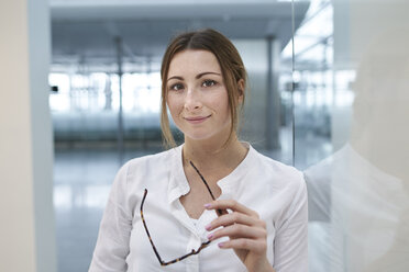 Portrait of confident young businesswoman holding glasses - PNEF01378