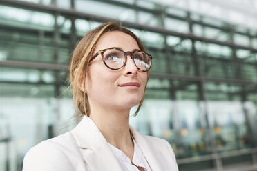 Portrait of young businesswoman wearing glasses in front of a building - PNEF01382