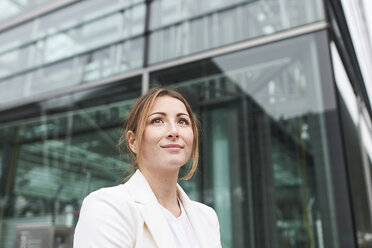 Porträt einer jungen Geschäftsfrau vor einem Gebäude mit Blick nach oben - PNEF01383