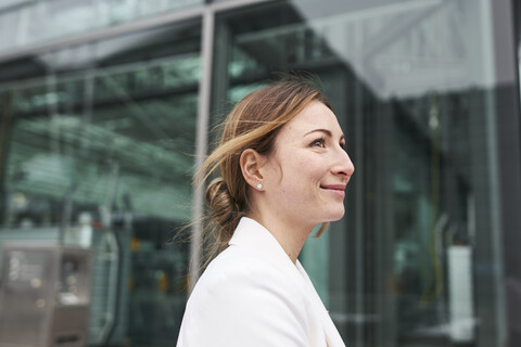 Porträt einer lächelnden jungen Geschäftsfrau vor einem Gebäude, lizenzfreies Stockfoto