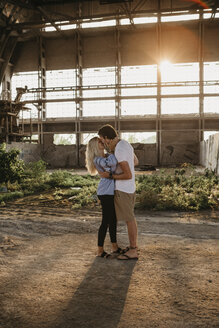 Junges Paar küsst sich in einer alten Halle bei Sonnenuntergang - LHPF00491