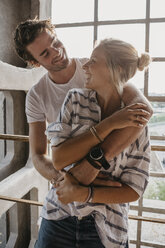 Happy young couple cuddling at the window - LHPF00504