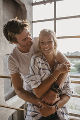 Happy young couple cuddling at the window - LHPF00506