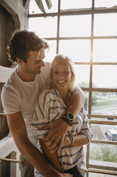 Happy young couple cuddling at the window - LHPF00507