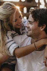 Happy young couple cuddling on old staircase at sunset - LHPF00524