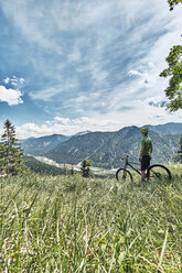 Deutschland, Bayern, Isartal, Karwendelgebirge, Mountainbiker auf Tour mit Pause auf Almwiese - WFF00072