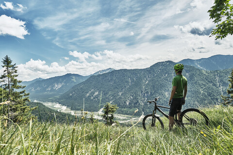 Germany, Bavaria, Isar Valley, Karwendel Mountains, mountainbiker on a trip having a break on alpine meadow stock photo