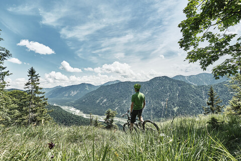 Deutschland, Bayern, Isartal, Karwendelgebirge, Mountainbiker auf Tour mit Pause auf Almwiese, lizenzfreies Stockfoto