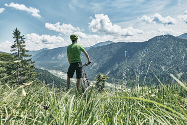 Germany, Bavaria, Isar Valley, Karwendel Mountains, mountainbiker on a trip having a break on alpine meadow - WFF00079
