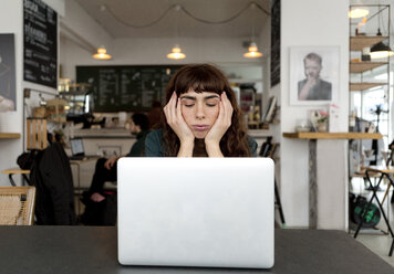 Frustrierte junge Frau mit Laptop in einem Café - FLLF00066