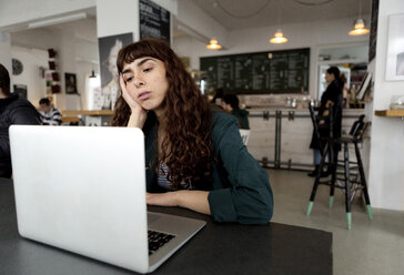 Frustrierte junge Frau mit Laptop in einem Café - FLLF00067