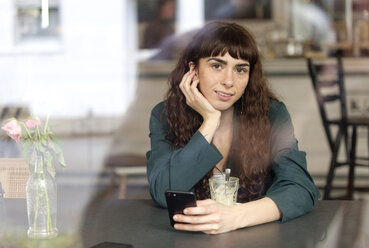 Portrait of smiling young woman in a cafe - FLLF00077