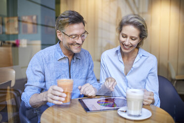 Happy woman and man using tablet in a cafe - PNEF01385