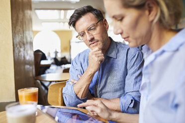 Focused woman and man using tablet in a cafe - PNEF01390