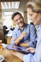 Smiling man and woman with tablet in a cafe - PNEF01391